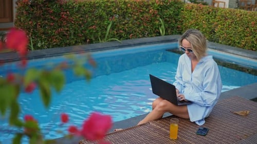 Young Woman Using Laptop Near the Swimming Pool