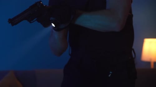 Man Holds Handgun with Flashlight in Dark Room