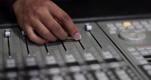 Closeup hands working a control mixer in a recording studio