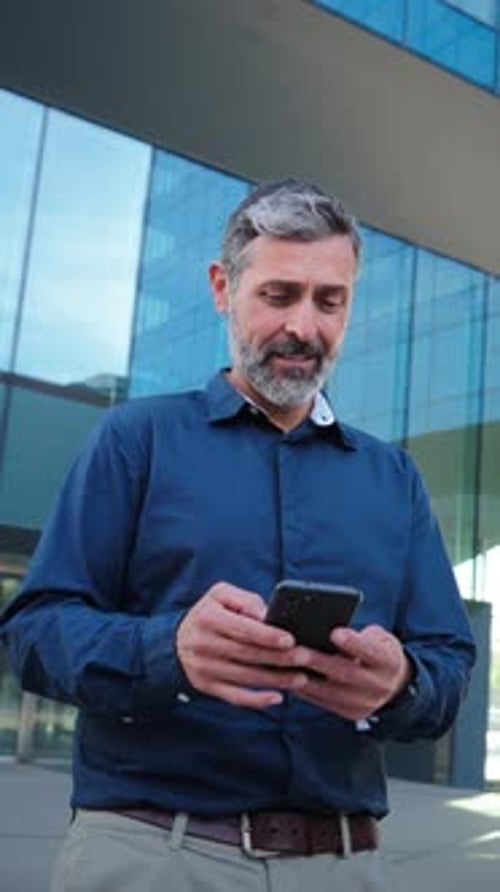 Vertical Video Real Mature Male Worker Watching a Finance App on His Cellphone Middle Aged Person