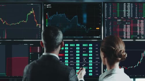 трейдер за несколькими мониторами с графиками