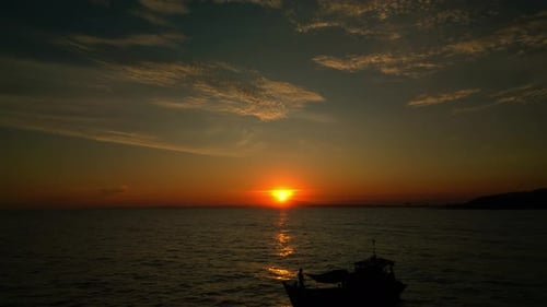 Flying Along the Sea Against the Background of a Sunset and a Fishing Boat Fishermen in the Sea are