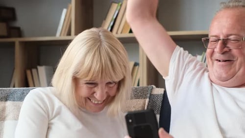 Senior Couple Laughing Together While Looking at Phone