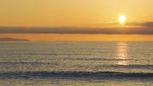 Black Sea and Beach Nearby Against a Sky with Clouds and a Dawn Sun