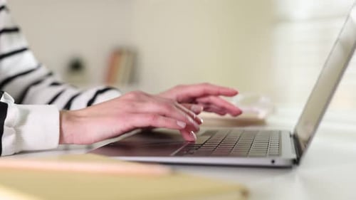 Frau arbeitet drinnen am Laptop am weißen Tisch, Nahaufnahme