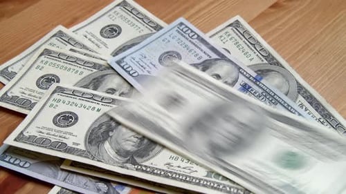 Pile of One Hundred Dollar Bills on Wood Surface