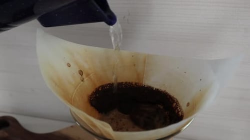 Hot Brewed Coffee Dripping From Paper Filter Into Glass Pot - Close Up