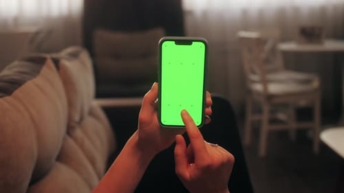 Woman Lying on Sofa in Modern Cozy Living Room Using Smartphone with Chroma Key Green Screen