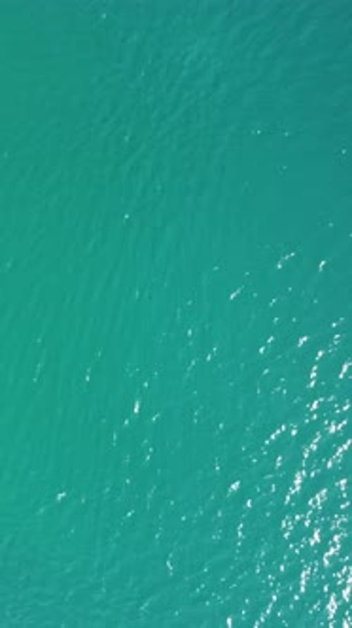 Vertical Aerial View on Sea Water Surface Camera Flies Over Clear Sea Water Sun Glare Abstract