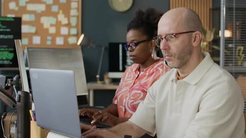 Focused Multiethnic Team of Programmers Coding on Computers in Office