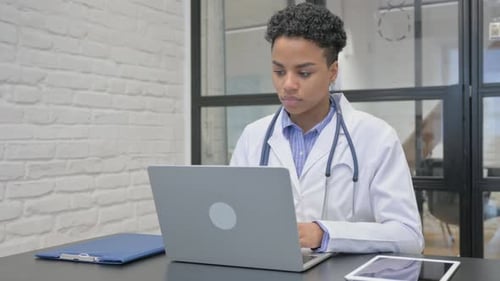 African Female Doctor Working on Laptop in Office