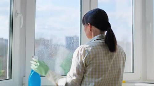 Woman Cleaning Windows at Home Using Spray and Microfiber Cloth