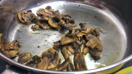 Frying mushrooms in pan on kitchen stove for dinner