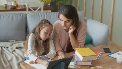 Woman Helping Young Girl Study At Home