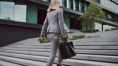 Elegant Woman Ascends Steps to Modern Office Building
