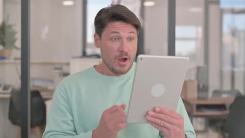 Man Celebrating Success While Using Digital Tablet