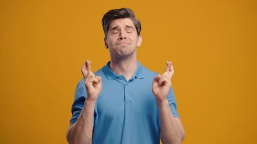 Handsome Man Crossing Fingers Praying with Hopeful Expression Silently Prays