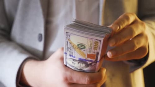Man Counts Stack of Hundred Dollar Bills