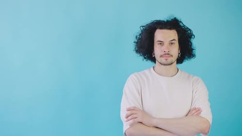 In a Minimalist Studio a Confident Young Man with Curly Hair Exudes Calm and Contemporary Vibes in a