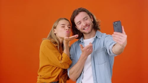 Couple Takes Selfie on Smartphone Grimacing in Orange Studio