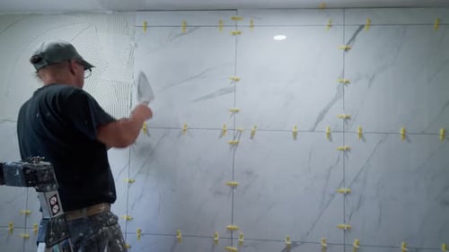 Man Installing Marble Tiles on Wall in Bathroom