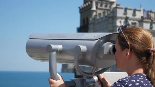 A Woman on the Observation Deck Looks Through Stationary Binoculars at the Sea