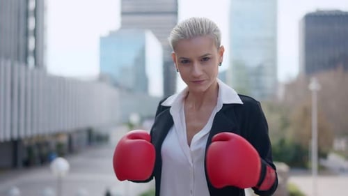 Businesswoman Clashing Boxing Gloves and Standing in Guard Position Outdoors