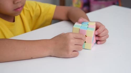Child Solving Colorful Cube Puzzle at Table
