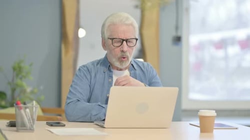 Frustrated Senior Man Tearing Document at Desk
