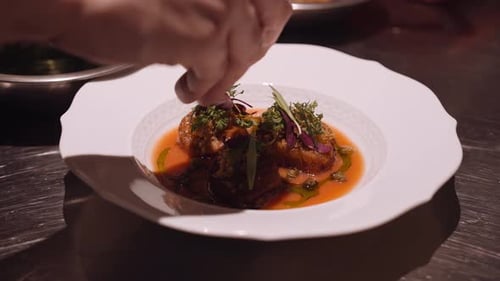 Close up panning shot of a delicious Italian dish prepared by the cook on a round white plate.