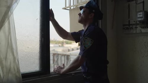 Police officer checking crime scene for clues during investigation in a building staircase window in