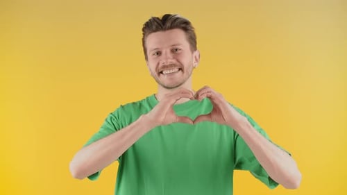 Smiling Man Makes Heart Shape with Hands