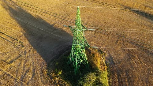 High voltage electricity tower in rural field, power supply to countryside village, drone view