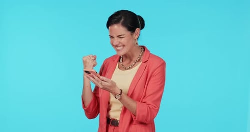 Excited woman, celebration and phone in studio for success, prize or bonus on fintech app by blue