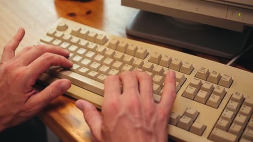 Hombre trabajando y jugando en una computadora retro, ingeniero de TI con una computadora antigua en casa usando una vieja