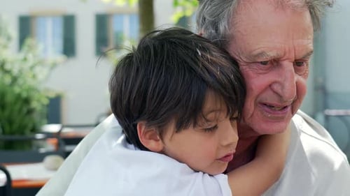 Grandfather Embraced by Grandson in Outdoor Urban Setting