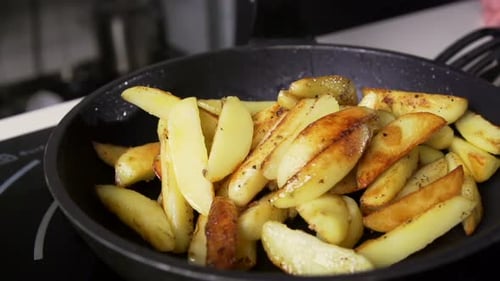 Golden potatoes frying in olive oil slow motion point of view homemade healthy lunch