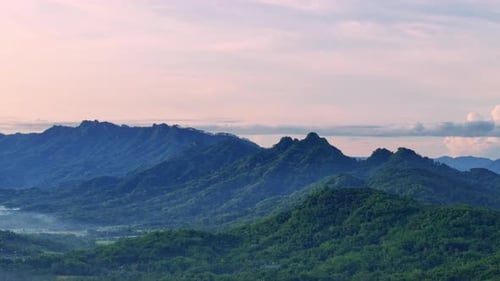 Panoramic panning drone view of forest and mountainous landscape and sunrise sky