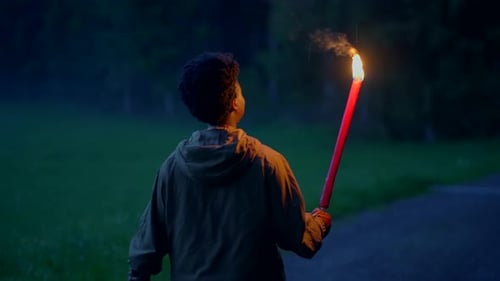 Young Adult Walks With Burning Torch at Night
