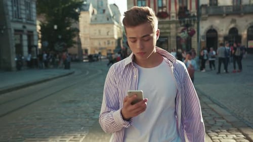 Serious Young Man Walk on Street Use Phone Look Around Portrait Sunlight Work Mobile Gadget Outside