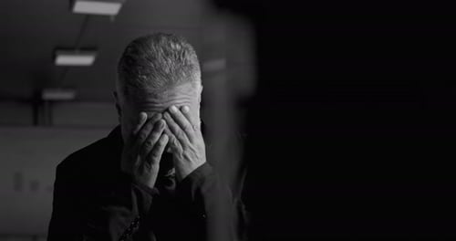 Distressed Man Rubs His Head in Black and White