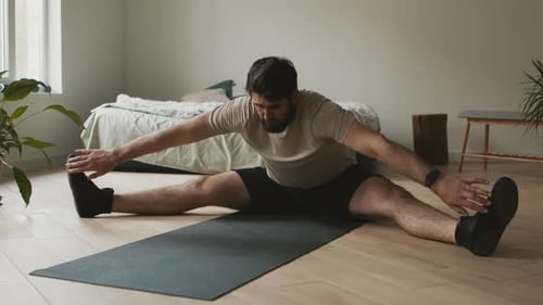 Bearded Man Stretching Hamstrings on Yoga Mat
