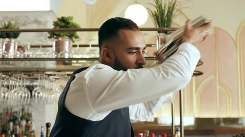 Young Focus Mixologist Shaking Cocktail Shaker to Make Classic Daiquiri Cocktail In