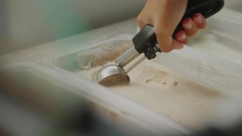Nahaufnahme einer Hand, die einen Eislöffel hält, Eiskugel macht, gefrorene Leckerei