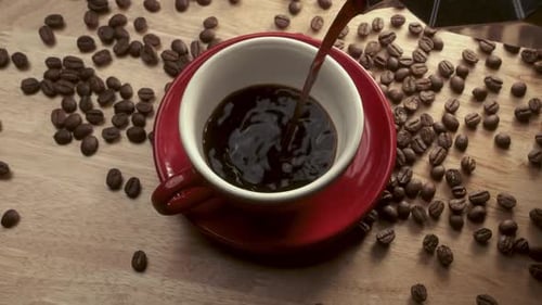 Coffee Being Poured into Cup with Coffee Beans
