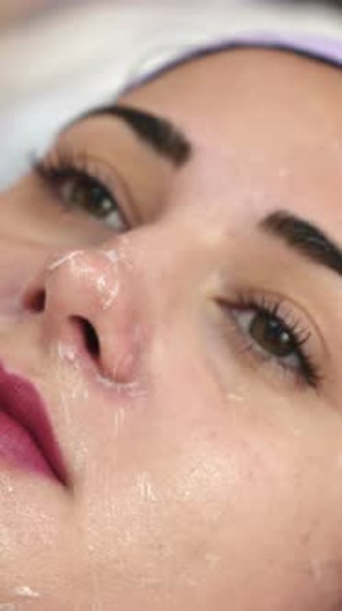 Beautiful young woman getting cosmetic mask in spa salon. Cosmetic facial treatment.