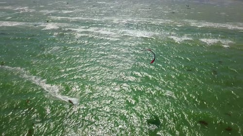 Aerial of Many Kiteboarders with Colorful Kites Flying Over the Blue Sea Lagoon Ride on Kiteboards