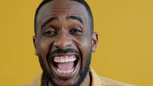 Man Laughing in Close-Up Against Yellow Background