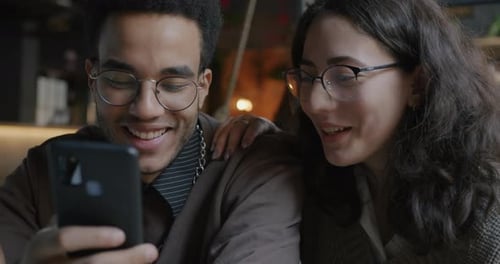 Slow Motion of Joyful Young Couple Using Smartphone and Laughing Together in Cafe