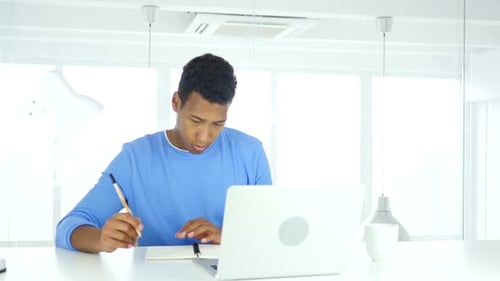 Young Adult Working at Laptop in Modern Office